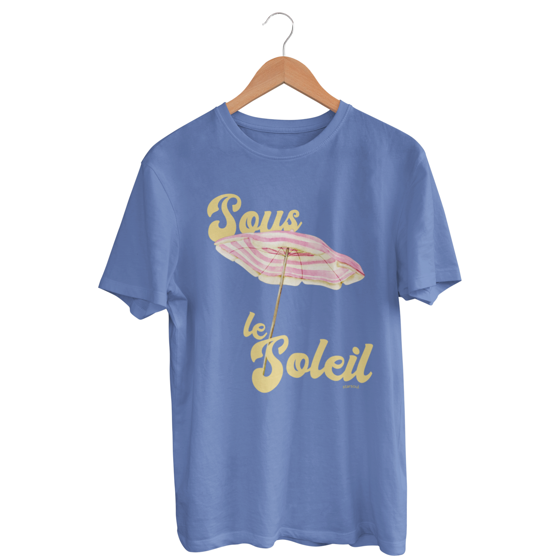 blue t-shirt featuring a pastel-colored beach umbrella graphic. The text on the shirt reads “Sous le Soleil” in a retro yellow font, which translates to “Under the Sun” in French. All proceeds go to environmental initiatives.