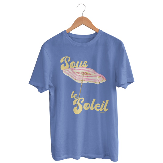 blue t-shirt featuring a pastel-colored beach umbrella graphic. The text on the shirt reads “Sous le Soleil” in a retro yellow font, which translates to “Under the Sun” in French. All proceeds go to environmental initiatives.