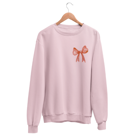 Pink vintage Christmas sweater with small red bow chest print and JOY sleeve — charity sweater donating toys to children in need