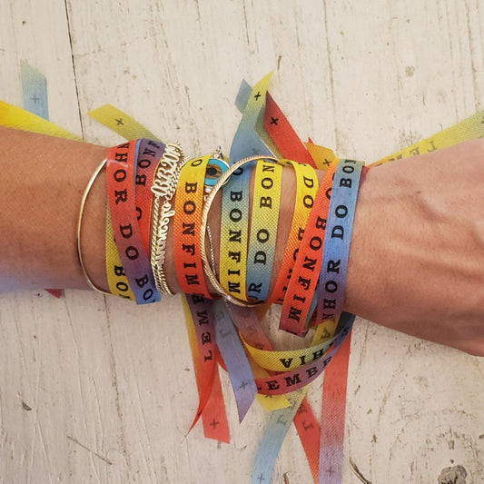 Charity t-shirt subscription box. All proceeds from these bracelet  will support the cause of the month at time of purchase. Brazilian bonfim bracelet for wishes, good luck, karma. All proceeds go to charity. Photo: rainbow colored bracelets